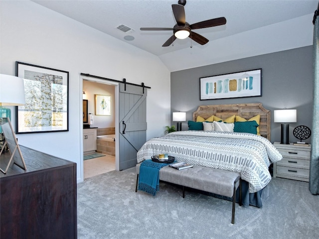 carpeted bedroom featuring ensuite bathroom, a barn door, ceiling fan, and vaulted ceiling