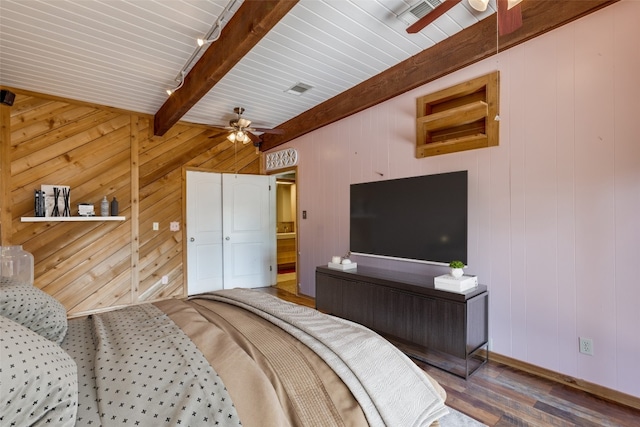 bedroom featuring wood walls, hardwood / wood-style flooring, ceiling fan, and beam ceiling