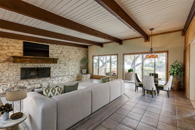 living room with a fireplace, beamed ceiling, wood ceiling, and plenty of natural light