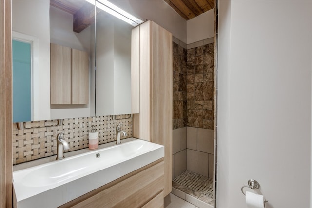 bathroom with vanity, backsplash, and tiled shower