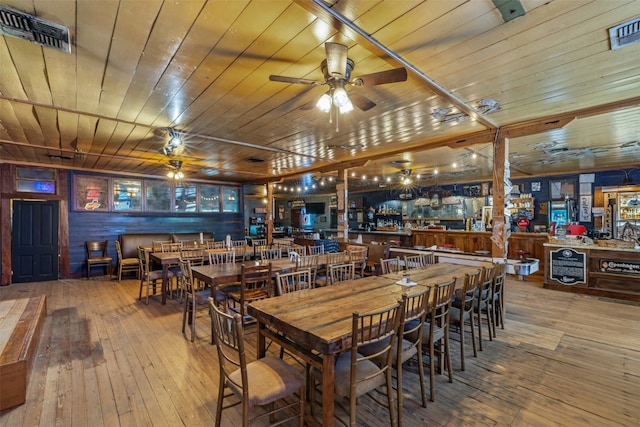 dining room featuring wooden ceiling, light hardwood / wood-style floors, ceiling fan, and wood walls