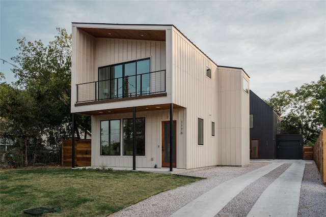 contemporary home featuring a balcony and a front yard