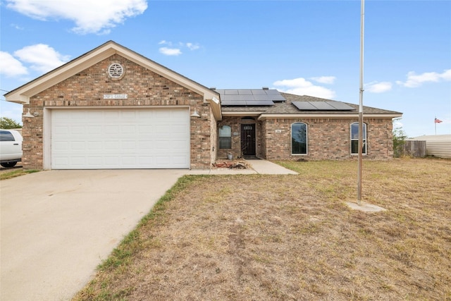 ranch-style house with a garage, solar panels, and a front yard