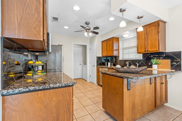 kitchen featuring dark stone counters, backsplash, decorative light fixtures, a kitchen bar, and kitchen peninsula