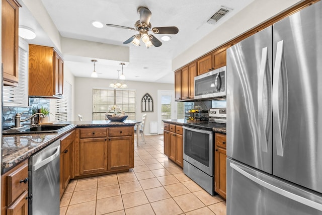 kitchen with stainless steel appliances, decorative light fixtures, light tile patterned floors, sink, and kitchen peninsula