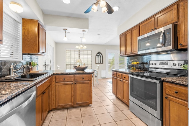 kitchen featuring tasteful backsplash, stainless steel appliances, pendant lighting, sink, and kitchen peninsula