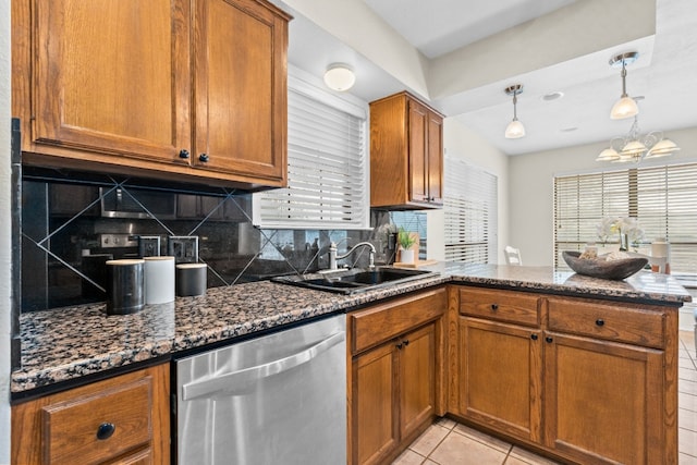 kitchen featuring hanging light fixtures, sink, decorative backsplash, dark stone countertops, and stainless steel dishwasher