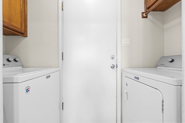 clothes washing area with washer and clothes dryer and cabinets