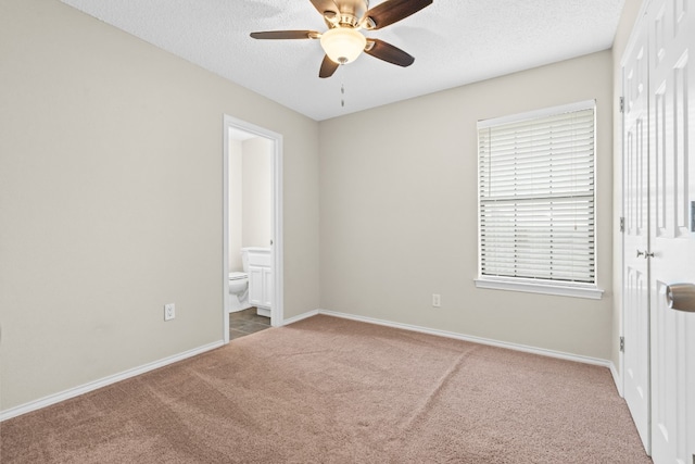 unfurnished bedroom with ensuite bathroom, carpet flooring, a textured ceiling, and ceiling fan