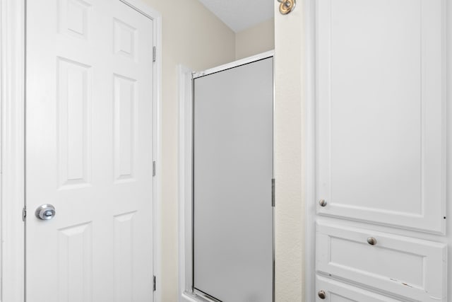 bathroom with walk in shower and a textured ceiling