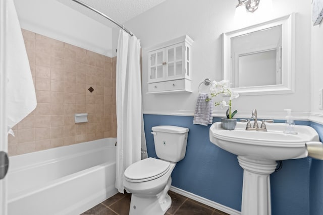 bathroom with toilet, shower / tub combo, a textured ceiling, and tile patterned floors