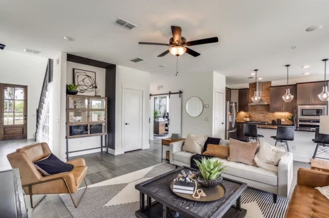 living room with dark wood-type flooring, a barn door, and ceiling fan