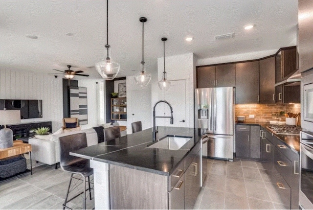 kitchen with a center island with sink, stainless steel appliances, dark brown cabinets, sink, and ceiling fan