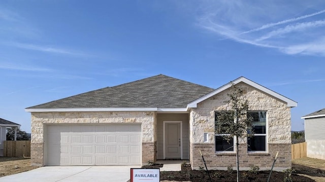 view of front facade with a shingled roof, concrete driveway, a garage, and fence