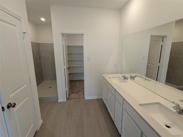 full bathroom with a sink, wood finished floors, a stall shower, and double vanity