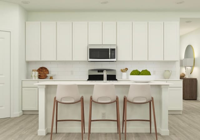 kitchen featuring light hardwood / wood-style flooring, white cabinetry, stainless steel range oven, and a kitchen island with sink