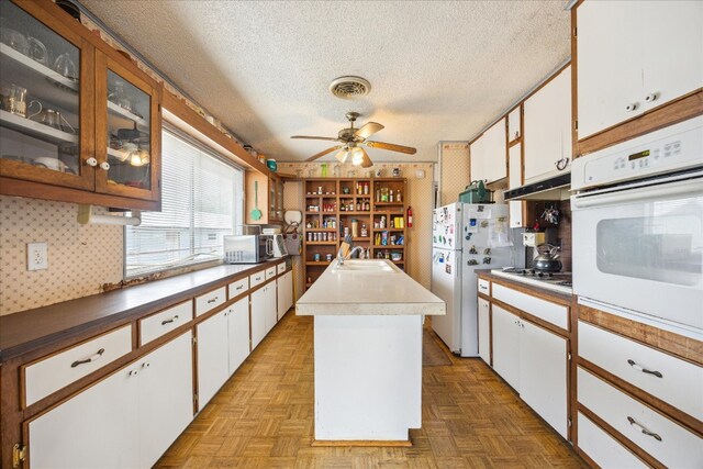 kitchen featuring white cabinetry, light parquet floors, white appliances, and a kitchen island