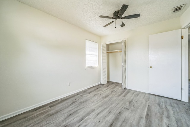 unfurnished bedroom with a textured ceiling, light hardwood / wood-style floors, ceiling fan, and a closet