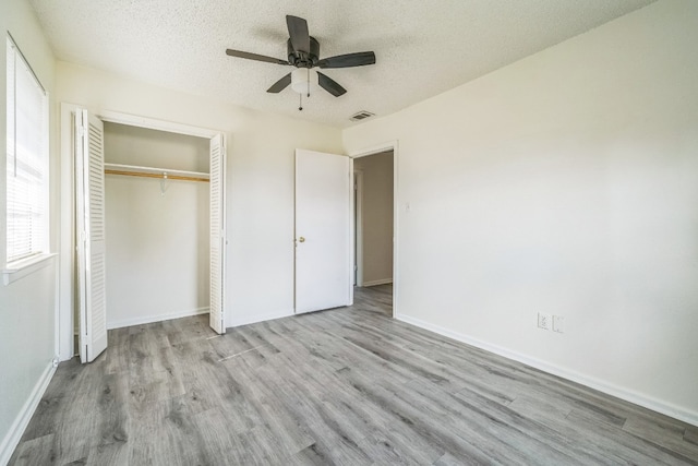 unfurnished bedroom with a closet, light hardwood / wood-style floors, a textured ceiling, and ceiling fan