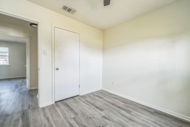 unfurnished bedroom featuring ceiling fan, a textured ceiling, and light wood-type flooring