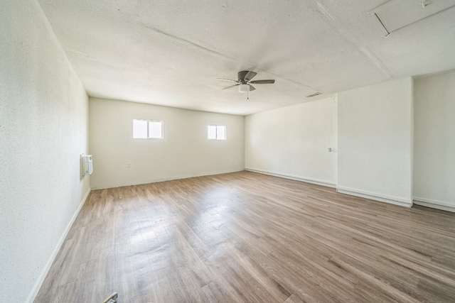 empty room with ceiling fan, a textured ceiling, and light wood-type flooring