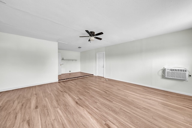 spare room with a textured ceiling, light wood-type flooring, ceiling fan, and a wall mounted air conditioner