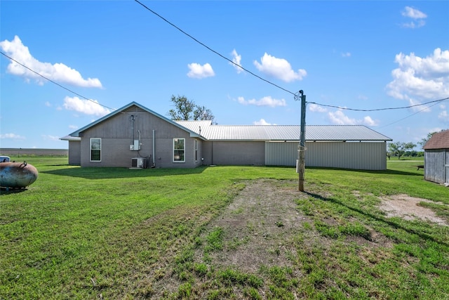 rear view of property featuring a yard, cooling unit, and an outdoor structure