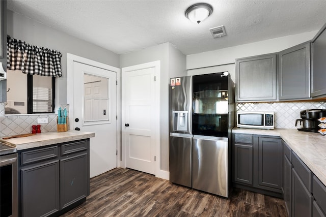 kitchen with stainless steel appliances, tasteful backsplash, dark hardwood / wood-style flooring, a textured ceiling, and gray cabinets