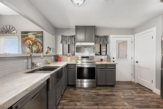 kitchen featuring backsplash, gray cabinets, dark hardwood / wood-style flooring, and stainless steel appliances