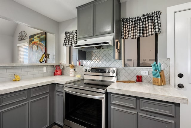 kitchen featuring backsplash, gray cabinetry, electric range, and lofted ceiling