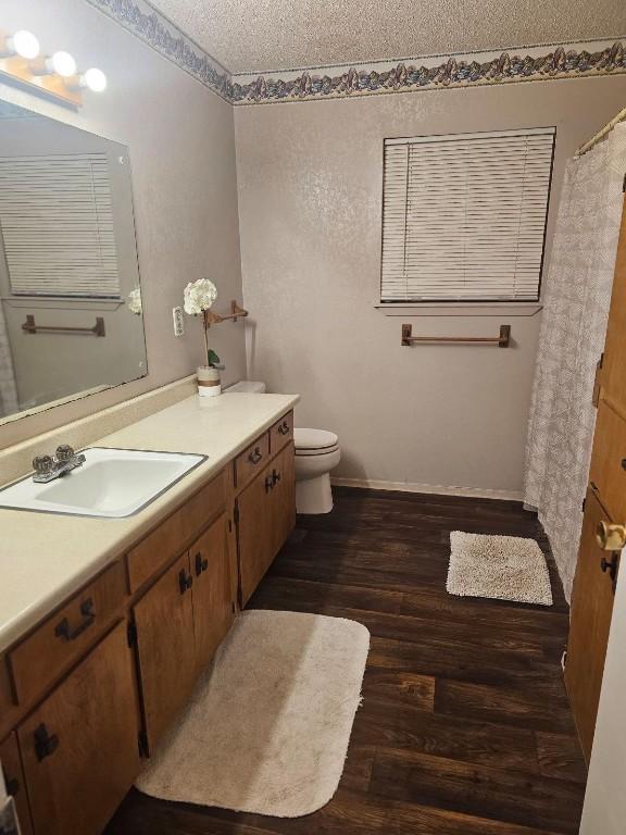 bathroom featuring hardwood / wood-style floors, vanity, toilet, and a textured ceiling