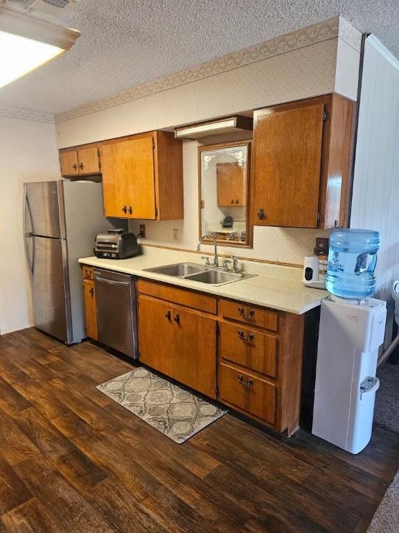 kitchen featuring a textured ceiling, sink, stainless steel appliances, and dark wood-type flooring