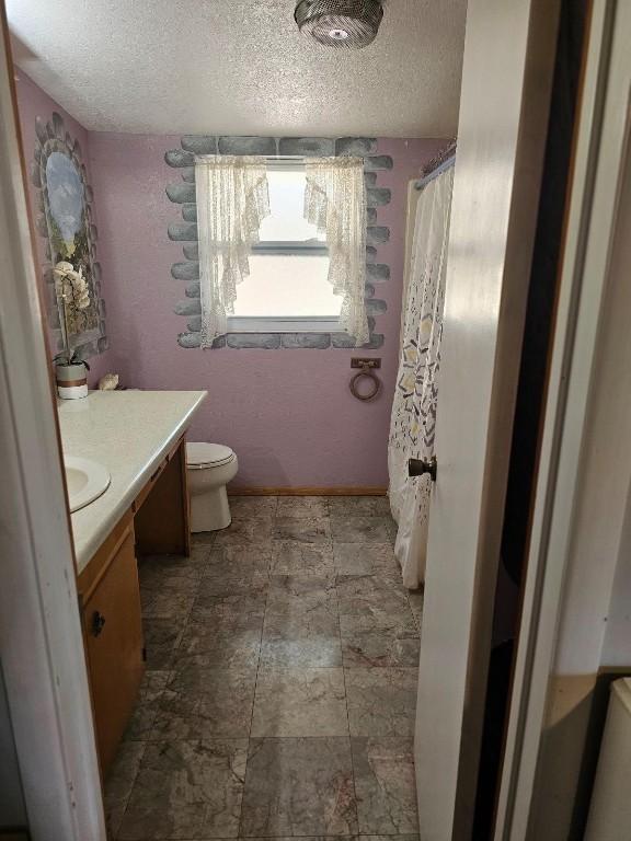 bathroom featuring vanity, a textured ceiling, and toilet