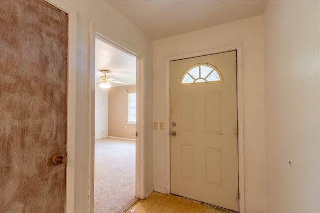 carpeted entrance foyer featuring ceiling fan and a healthy amount of sunlight