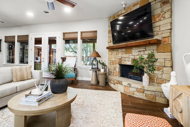 living room featuring ceiling fan, a fireplace, and dark wood-type flooring