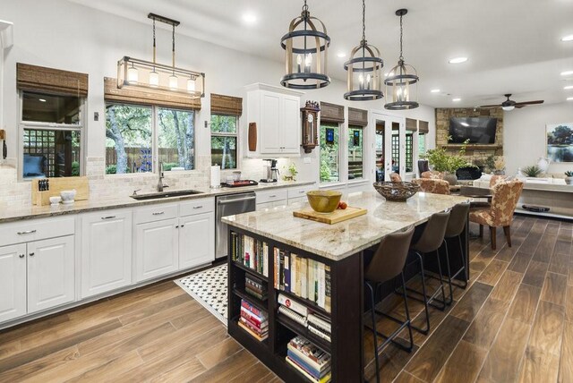 kitchen with dishwasher, hardwood / wood-style floors, white cabinets, and a kitchen island