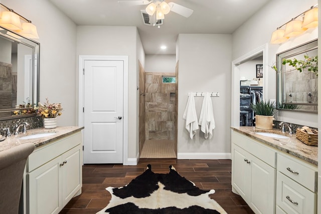 bathroom with a tile shower, ceiling fan, vanity, and hardwood / wood-style flooring