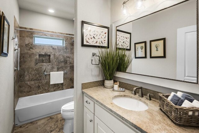 full bathroom featuring vanity, tiled shower / bath combo, and toilet