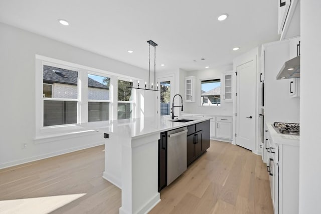 kitchen with sink, an island with sink, appliances with stainless steel finishes, light hardwood / wood-style floors, and white cabinetry