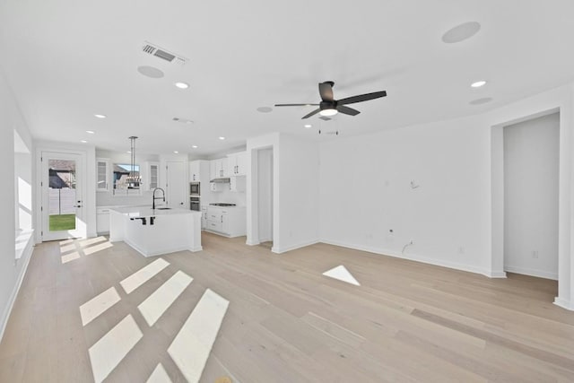 unfurnished living room featuring ceiling fan, sink, and light hardwood / wood-style flooring