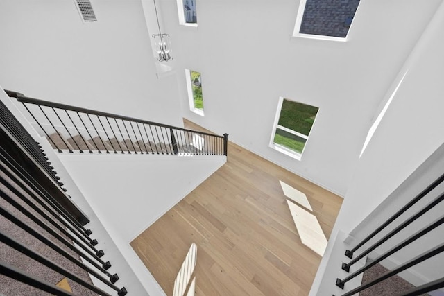 stairway with hardwood / wood-style floors and an inviting chandelier