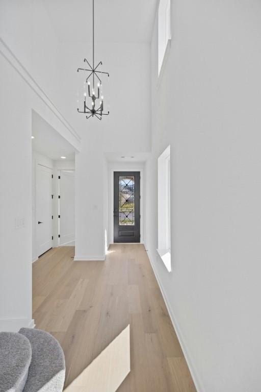 foyer entrance featuring light hardwood / wood-style floors, a high ceiling, and an inviting chandelier