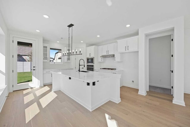 kitchen with white cabinetry, hanging light fixtures, a spacious island, and light hardwood / wood-style floors