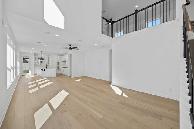 unfurnished living room featuring ceiling fan, sink, and light hardwood / wood-style floors