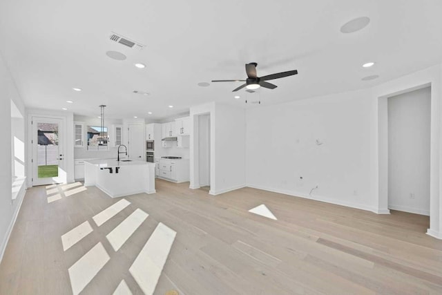 unfurnished living room featuring light hardwood / wood-style flooring, ceiling fan, and sink