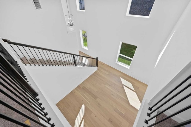 stairs featuring hardwood / wood-style flooring and an inviting chandelier