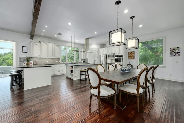 dining room featuring dark hardwood / wood-style flooring, beamed ceiling, and a healthy amount of sunlight