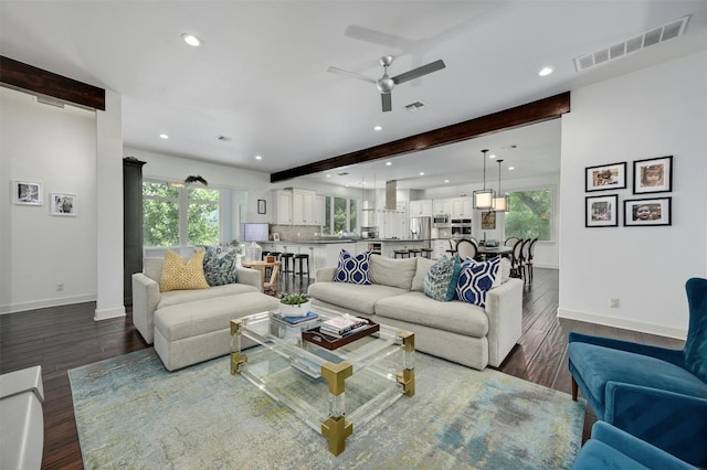 living room featuring dark hardwood / wood-style flooring, beamed ceiling, and ceiling fan