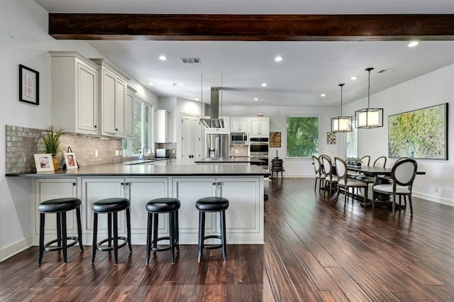 kitchen with island exhaust hood, decorative light fixtures, dark hardwood / wood-style flooring, decorative backsplash, and kitchen peninsula