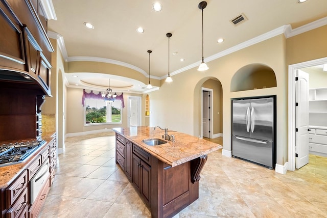 kitchen featuring ornamental molding, a center island with sink, appliances with stainless steel finishes, light stone countertops, and sink